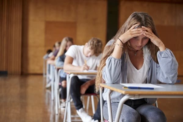 Girl in class with head in hands at desk, teen anxiety research studies