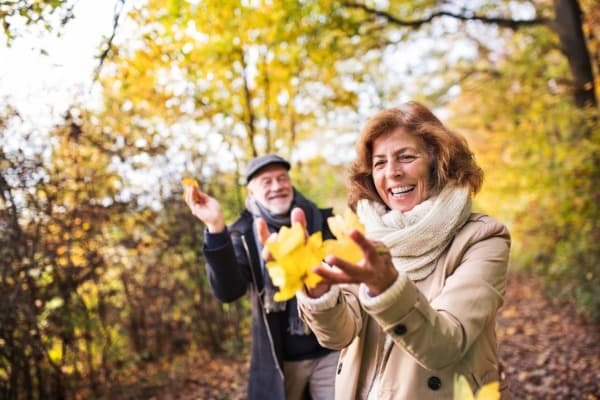 Older couple, fall weather, woman holding leaves, both laughing, memory and aging, free memory screen